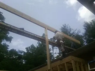 Carpenter setting a ridge beam over a new addition frame — Ice Dam Removal by Roofing Brothers in Colquitt