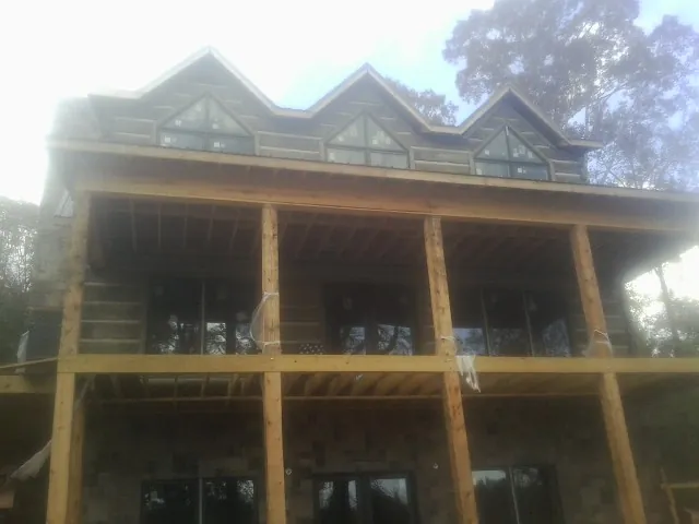Dormers and porch framing on a large log home under construction — Roof Coating work by our crew in Colquitt
