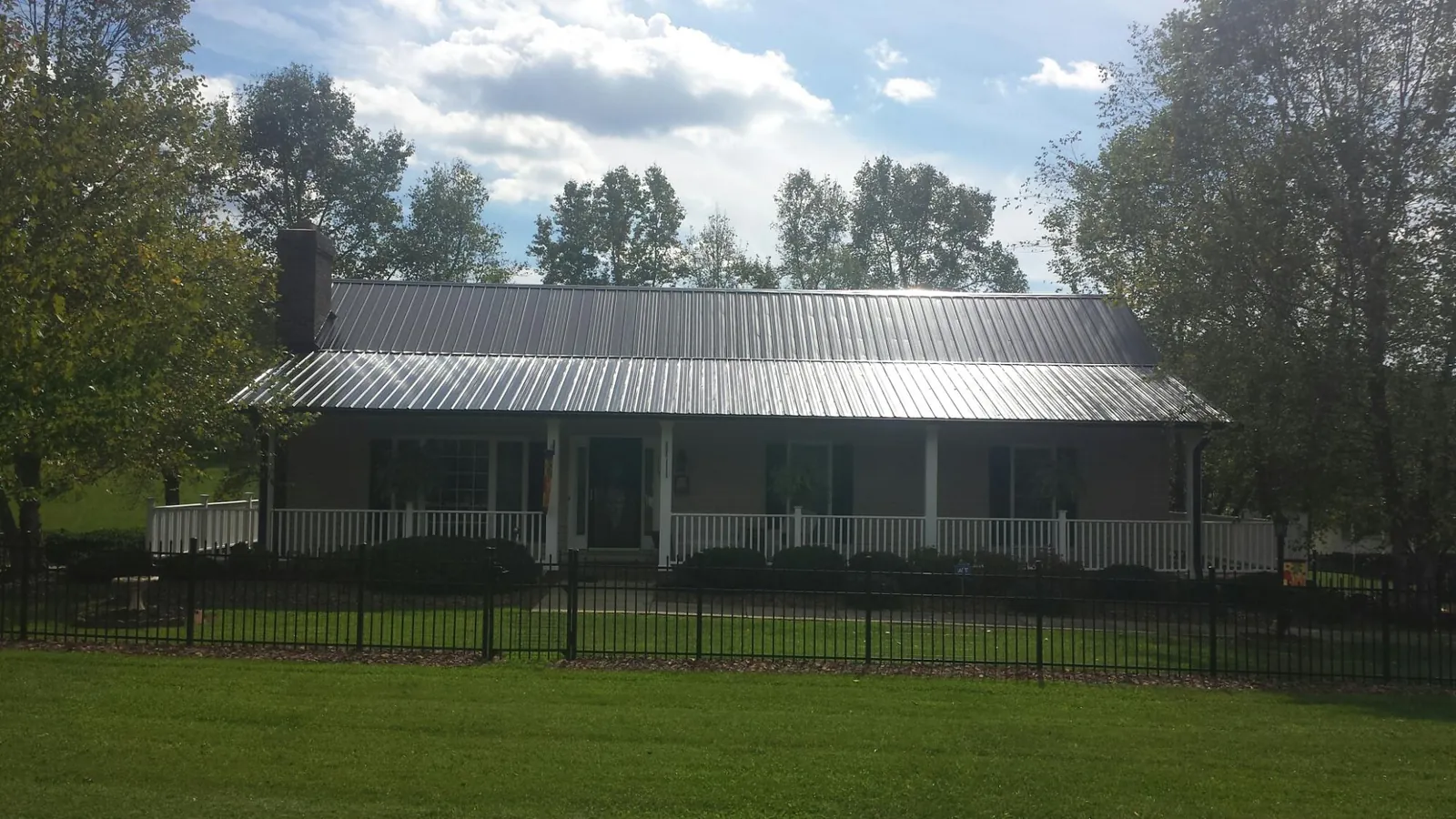 Gray metal roof on a brick ranch with a full width front porch — Gutter Guard Installation work by our crew in Colquitt
