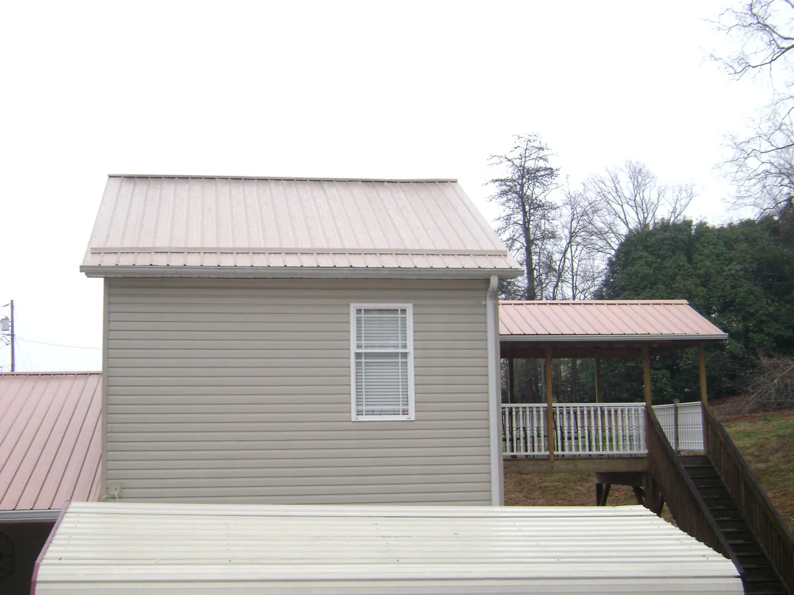 Tan metal roofs on a two story addition and attached porch, from a Roof Replacement job in Colquitt