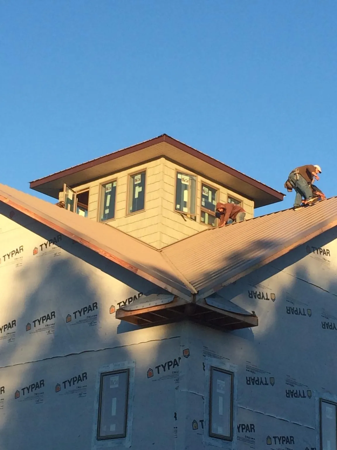 Roofers working around a rooftop cupola on a new metal roof at sunset — Roof Waterproofing in Colquitt by Roofing Brothers
